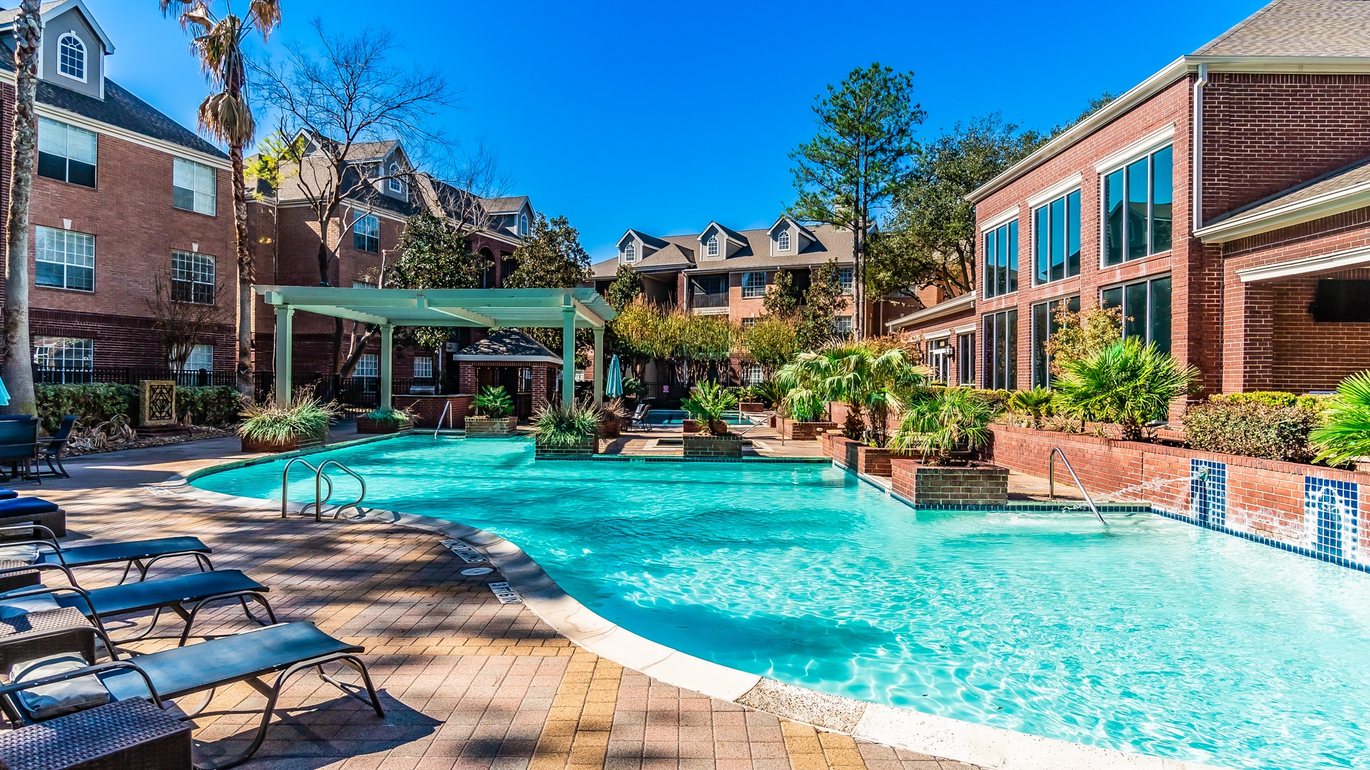 A large swimming pool surrounded by lounge chairs and trees.